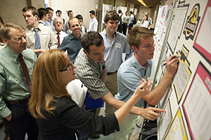 Students writing on a conference poster