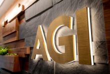 AGI in backlit gold lettering against a slate and wood backdrop. 