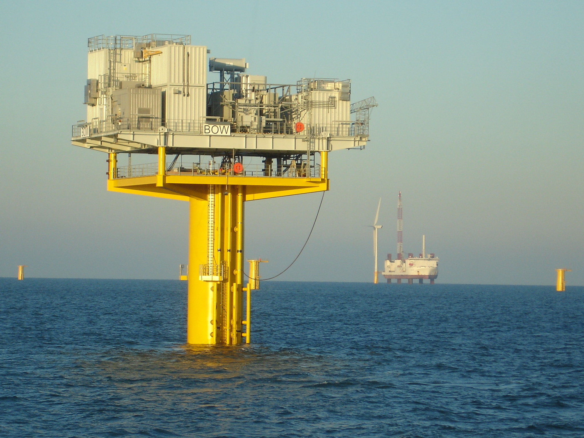 Offshore wind platforms and turbines in a calm ocean.