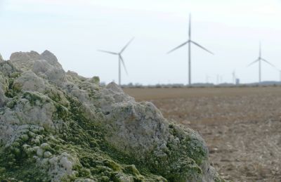 A grey rock fills the foreground, with two large windmills in the background