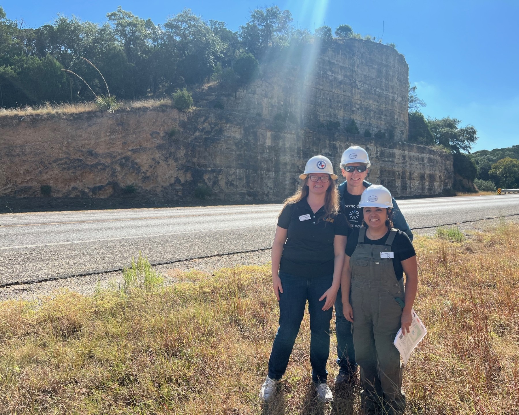 three women standing in front of a roadcut