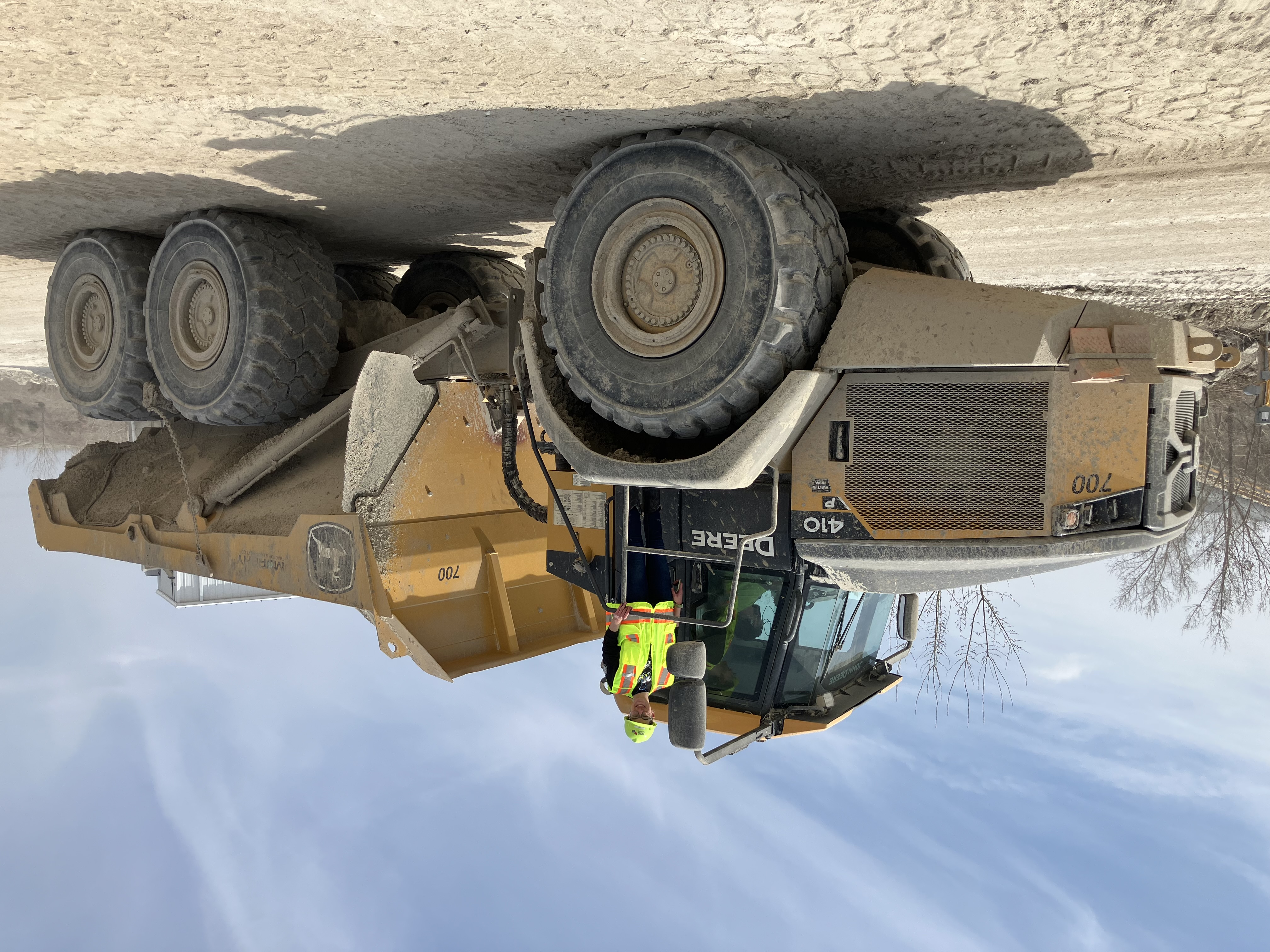 Mine Equipment; teacher for scale a teacher in PPE on top of a dump truck