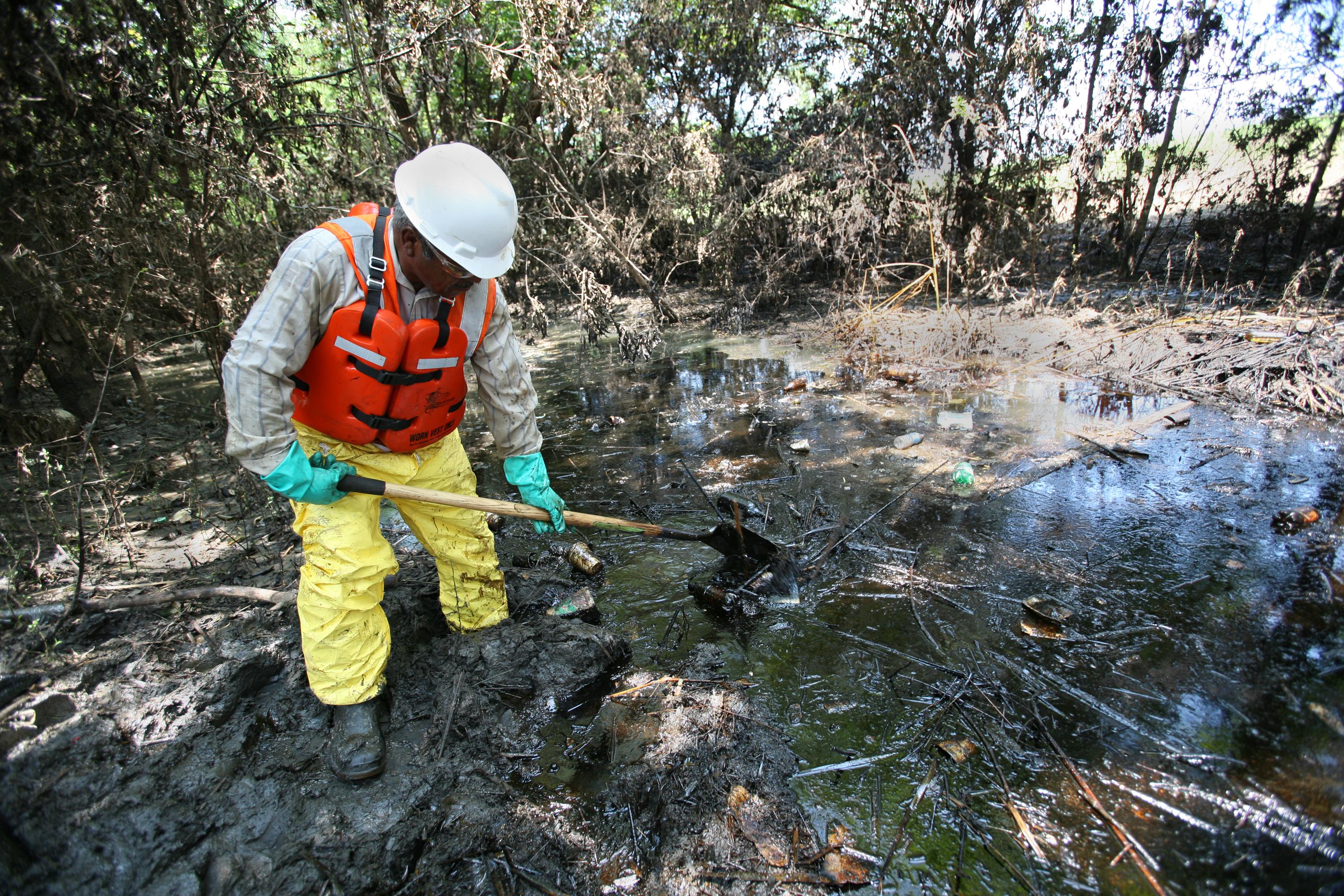 A contractor works to remove oil pools left after a spill from a refinery in Coffeyville, Kansas, contaminated floodwaters of the Verdigris River in 2007. Image credit: Leif Skoogfors/U.S. Federal Emergency Management Agency. A contractor works to remove oil pools left after a spill from a refinery in Coffeyville, Kansas, contaminated floodwaters of the Verdigris River in 2007.