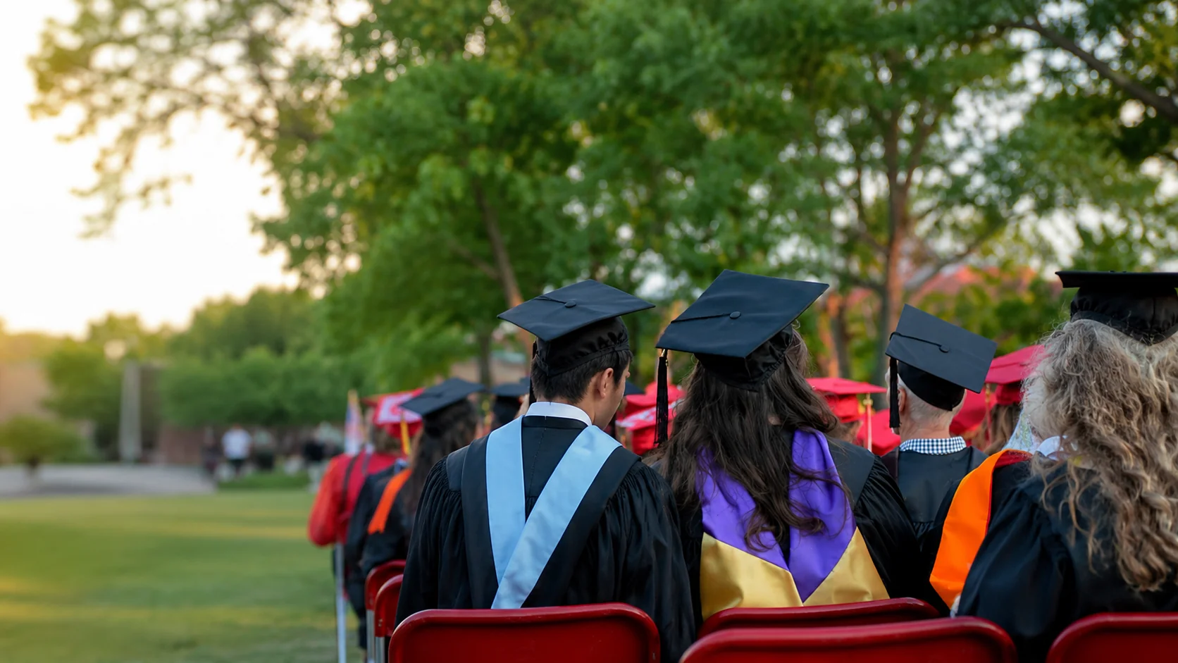 Faculty sitting in chairs at a graduation