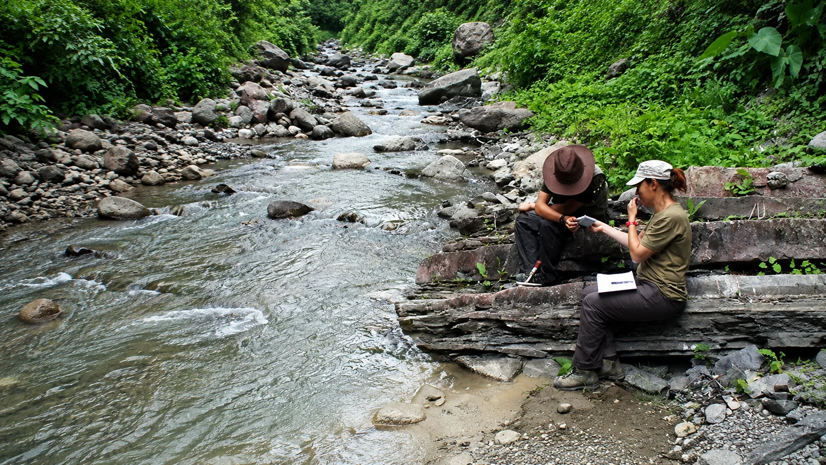 Geoscientists collecting water samples from a river.